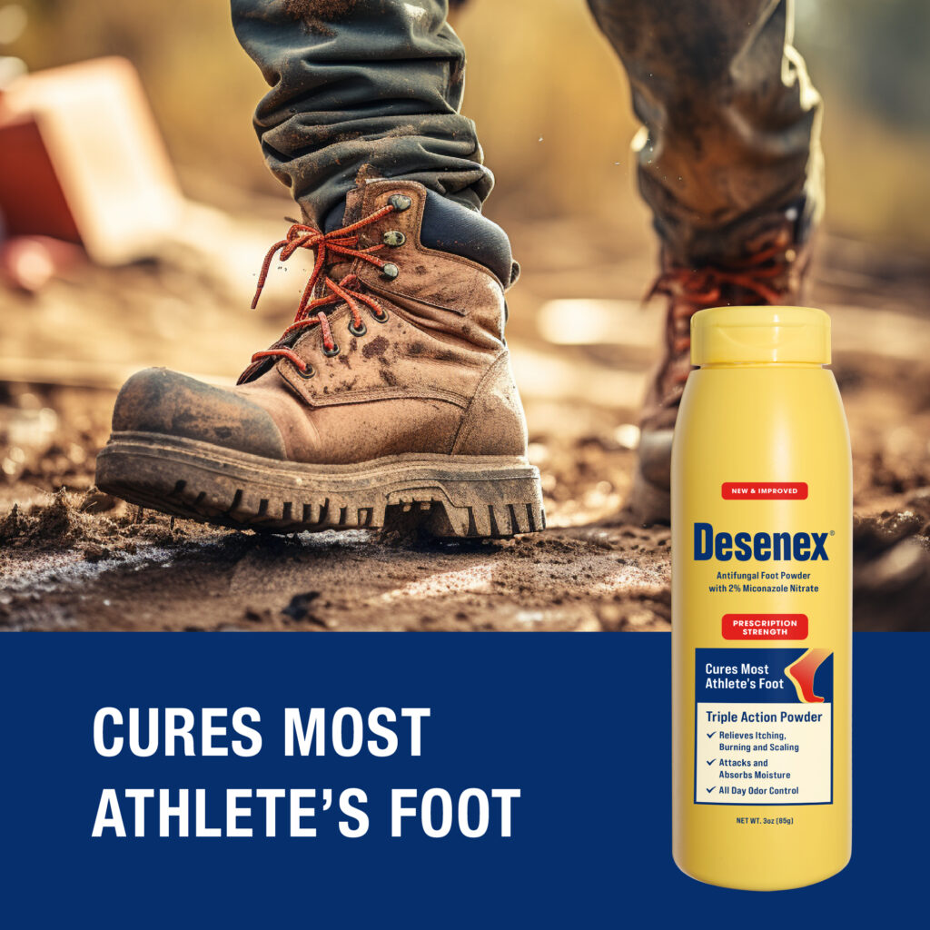 A pair of booted feet walk along a dirt path, alongside a bottle of Desenex Athlete's Foot Powder.